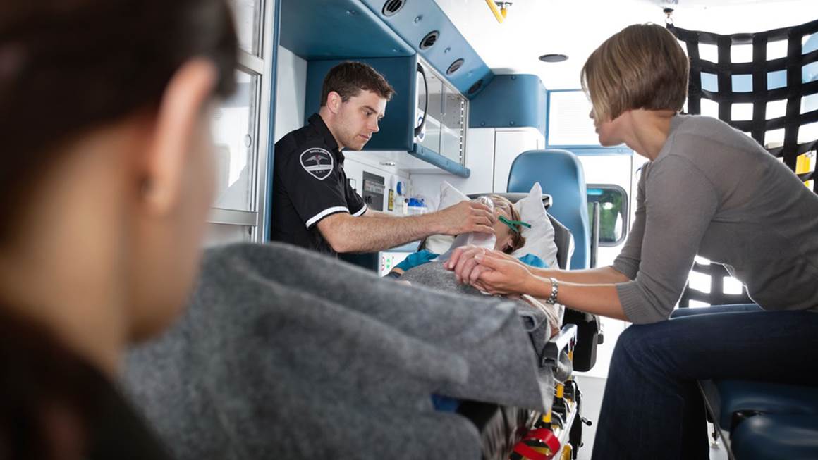 Senior woman being given oxygen in an ambulance caregiver at side